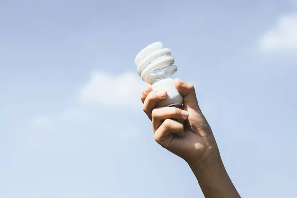Recyclable electric waste held in hand up on sky background. Hand holding light bulb for recycle reduce and reuse concept to promote clean environment with recycling management. Gyre