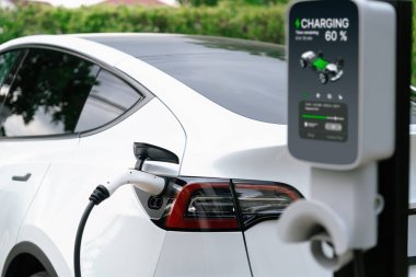 Elektrikli araç portuna bağlı EV şarj prizi kolu şarj istasyonundan şarj oluyor. Modern tasarlanmış EV araba ve daha iyi bir gelecek konsepti için temiz enerji sürdürülebilirliği. Eşzamanlama