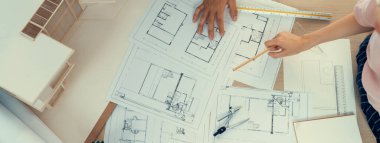 Mimari planlar toplantı masasında dağıtılırken profesyonel mimar el çabukluğu planlara işaret ediyor. Yaratıcı tasarım takım çalışması tartışma konsepti. Üst Manzara. Filizlenen.