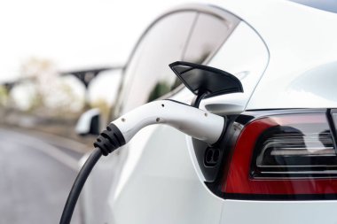 Kapalı EV şarj kolu fişe takıldı veya elektrikli arabaya bağlandı, EV araba aküsünü temiz çevre için sıfır CO2 emisyonu ile alternatif ve sürdürülebilir enerjiyle şarj etti. Kalıcı