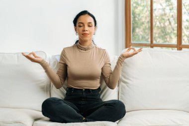 Genç Afrikalı Amerikalı kadın, zihinsel sağlık gücünü ve huzur dolu güzel yaşamı geliştirmek için ev oturma odasında çok dikkatli meditasyon yapıyor.