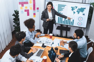 Modern toplantı odasındaki TV ekranında veri analizi paneliyle üst görünüm iş sunumu. İş adamlarının iş pazarlama stratejisini planlamak için beyin fırtınası yapması ya da birlikte çalışması. Uyum