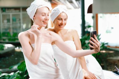 Beyaz havluyla güzel ciltli bir çift güzel kadın açık havada barışçıl doğal çevreyle çevrili bir şekilde fotoğraf çekiyorlar. Güzellik ve sağlıklı spa konsepti. Huzur.