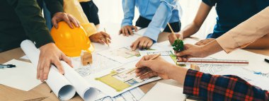 Profesyonel mimar, eko ev projesinde yeşil tasarım kullanımını planlı ve mimari ekipmanlarla tartışan mühendis ile işbirliği yapıyor. - Yakın çekim. Tanımlama.