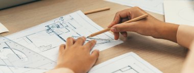 Profesyonel mimar, modern ofiste mimari ekipman ve mavi baskı dağınıklığı olan cetvel ölçüm uzunluğunu kullanarak bir plan çiziyor. - Yakın çekim. Tanımlama.