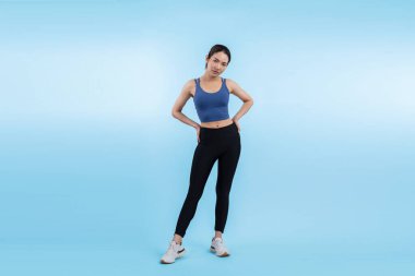 Spor giyim portresindeki tüm vücut Asyalı kadın gülümsüyor ve neşeli bir jest yapıyor. Çekici bir kızla egzersiz yapmak sağlıklı yaşam tarzını sürdürmeye yöneliktir. İzole edilmiş arka plan Vigorous