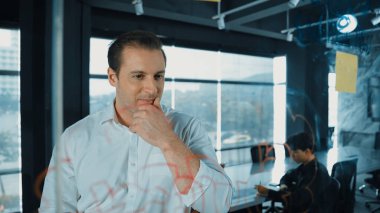 Akıllı iş adamı cam tahtanın önünde bir proje başlatmayı düşünüyor. Gülümseyen erkek proje yöneticisi yaratıcılık pazarlama stratejisini gösteren renkli yapışkan notlara bakıyor. Yönlendirici.