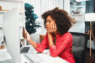 Genç Afrikalı iş kadını projesini ekran monitörü laptopuna odaklıyor, web sitesi bilgisayarındaki veri merkezini ve akıllı telefonu araştırıyor. Mekan teması sade renkte rahat bir odada çalışır. Tatlandırıcı.
