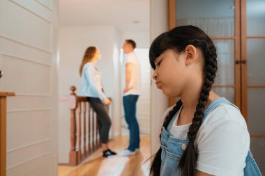Stresli ve mutsuz genç kız arka planda ebeveynleri tartışırken köşede ağlayıp üzülüyor. Evde aile içi şiddet ve travmatik çocukluk depresyona dönüşür. Eşzamanlama