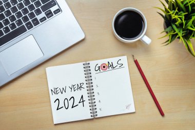 2024 Mutlu Yeni Yıl Kararları Hedef Listesi ve Planları Ayarlama - Yeni yıl hedefleri ve kararları planlama hakkında not defteriyle birlikte iş yeri masası. Değişim ve mutluluk kavramı.