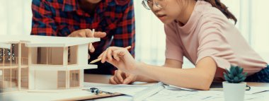 Akıllı mimar mühendis ve iç mimar birlikte çalışıyor ve ev modelini ölçmek için plan ve mimari ekipmanlarla toplantı masasında cetvel kullanıyor. Takım çalışması konsepti. Filizlenen.