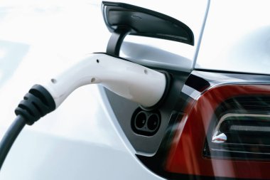Elektrikli araç portuna bağlı EV şarj prizi kolu şarj istasyonundan şarj oluyor. Modern tasarlanmış EV araba ve daha iyi bir gelecek konsepti için temiz enerji sürdürülebilirliği. Eşzamanlama