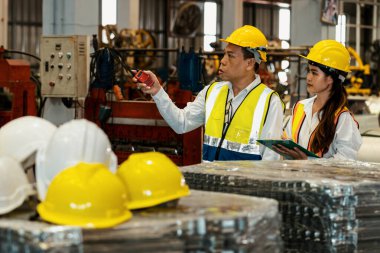 Fabrika ustabaşı ve mühendis çelik makinesi ve ağır endüstriyel malzeme kalitesinde ürün teftişi yapıyor. Makine güvenliği ve kalite kontrollü metal levha üretimi. Örnek gösteriliyor