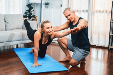 Spor giyim sektöründe aktif olan mutlu çift destekleyici ve evde yoga duruşunda birlikte yardımcı oluyorlar. Yoga egzersizi yapan sağlıklı bir erkek ve kadın yaşam tarzı. Etki