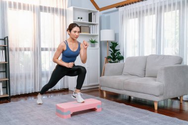 Enerjik bir kadın evde egzersiz yapıyor, kardiyo aerobik egzersizi yapıyor. Genç atletik Asyalı kadın mahareti ve dayanıklılık antrenmanı ev ödevi rutin konsepti olarak..