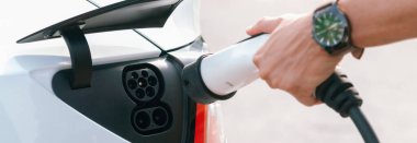 Kapalı el, şehrin ticari otoparkındaki elektrikli arabaların pillerini şarj etmek için EV şarj cihazı yerleştirdi. Sürdürülebilir çevre dostu şehir yolculuğu için şarj edilebilir EV araba. Panorama Çıkarı