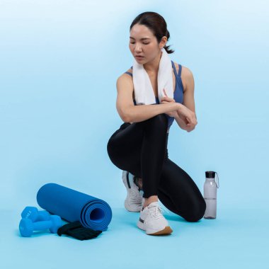 Atletik ve sportif Asyalı kadın yoğun kardiyo antrenmanından sonra dinleniyor. Stüdyoda sağlıklı egzersiz ve vücut bakımına uygun yaşam tarzı takibi izole edilmiş bir arka plan. Kuvvetli