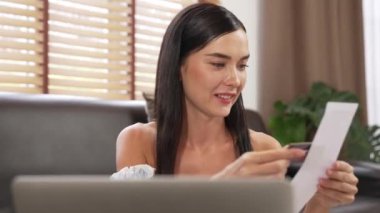 Mutlu bir kadın, faturalarını internet üzerinden öderken gülümseyerek kanepede oturur, tüm faturaları tek seferde ödemenin rahatlığını taktir eder ve kredi kartının sunduğu ödülün tadını çıkarır. Blithe