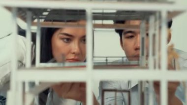 Ev modeli yapısını ölçmek için birlikte çalışan kooperatif mühendisi kapatın. Genç ve güzel mimar ev modelini ölçerken erkek mühendis performansını destekliyor. Tertemiz..