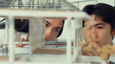 Ev modeli yapısını ölçmek için birlikte çalışan kooperatif mühendisi kapatın. Genç ve güzel mimar ev modelini ölçerken erkek mühendis performansını destekliyor. Tertemiz..