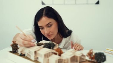 Genç ve güzel mimarın yakın çekimi mimari modeli ölçerken, modern toplantı odasındaki masadaki planlar ve mimari modeller arasında karşılaştırma yapıyor. Yaratıcı tasarım konsepti. Tertemiz..