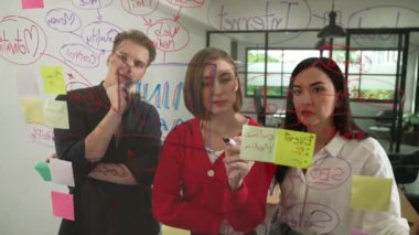 Genç yaratıcı şirket kurma ekibi fikir üretme ve sorunları renkli yapışkan notlar ve modern toplantı odasındaki zihin haritasını kullanarak çözme konusunda fikir üretiyor. Tartışıyoruz, birlikte çalışıyoruz. Tertemiz..