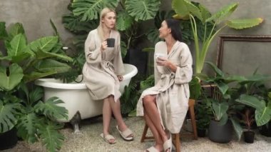 Modern otelde küveti olan tropikal ve egzotik bir spa bahçesi ya da bornozlu iki genç kadınla kahve içip, yemyeşil yeşilliklerle çevrili boş ve sağlıklı yaşam tarzının tadını çıkarmak. Blithe