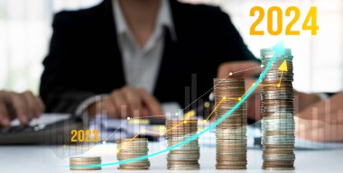 Büyüyen madeni para yığını iş yatırımını ve ekonomik büyümeyi simgeliyor. Finansal hedefe ulaşmak ve 2024 yılına maksimum kar sağlamak için finansal planlama yapan iş adamları. Kurnaz.