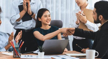 Çeşitli iş arkadaşları başarıyı şirket işyerindeki el sıkışma ve takım çalışmasıyla kutluyor. Çok kültürlü, mutlu profesyonellerden oluşan bir ekip ofiste tokalaşarak birlik oldular. Uyum