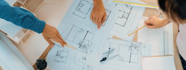 Mimari planlar toplantı masasında dağıtılırken profesyonel mimar el çabukluğu planlara işaret ediyor. Yaratıcı tasarım takım çalışması tartışma konsepti. Üst Manzara. Filizlenen.