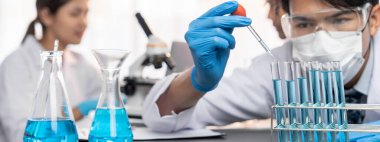 Kendini adamış bir grup bilim adamı tıbbi laboratuvarda kimyasal deney yapıyor. Aşı ilacı veya antibiyotik geliştirmek için pipetten deney tüpüne kesin miktarda sıvı döküyorlar. Neoterik