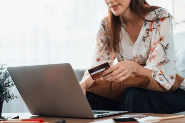Genç mutlu kadın internetten alışveriş yaparak ürün satın alırken aynı zamanda internet üzerinden online ödeme sistemi ile çevrimiçi mağaza platformundan en yüksek siber güvenlik tarafından korunan ürünler sipariş ediyor.