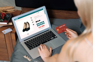 Genç bir kadın internet bankacılığı için kredi kartıyla dizüstü bilgisayar kullanıyor. Evinde online ödeme kapısı ile E ticareti yapıyor. Banka kartıyla modern ve kullanışlı online alışveriş. Blithe