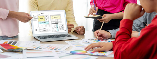 Cropped image of interior designer team discuss the material color while laptop displayed website wireframe designs for mobiles app and website. Creative design and business concept. Variegated.