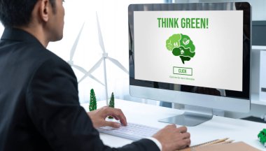 Ofiste çalışan iş adamı, CSR 'ın dışında daha yeşil bir çevre için bilgisayar ekranında güneş pili teknolojisiyle çevre dostu alternatif enerji planı veya projesi geliştiriyor. Döngü