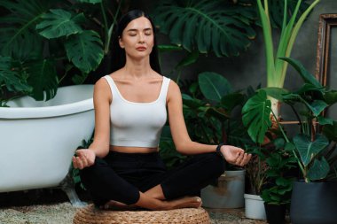 Sabah yoga ve meditasyon yapan genç bir kadın bitki yaprağıyla doğal bahçede yalnızlığın tadını çıkarıyor ve meditasyon yapıyor. Farkındalık aktivitesi ve sağlıklı zihin yaşam tarzı. Blithe