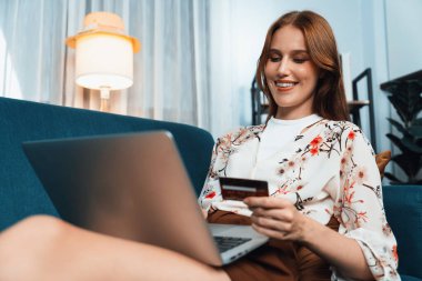 Genç mutlu kadın internetten alışveriş yaparak ürün satın alırken aynı zamanda internet üzerinden online ödeme sistemi ile çevrimiçi mağaza platformundan en yüksek siber güvenlik tarafından korunan ürünler sipariş ediyor.