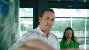 Yetenekli işadamı, cam duvara renkli yapışkan notlar yapıştırarak proje yöneticisine pazarlama fikrini sundu. Proje yöneticisi yatırımcıya projeyi gösteriyor, anlatıyor, gösteriyor. Yönlendirici.