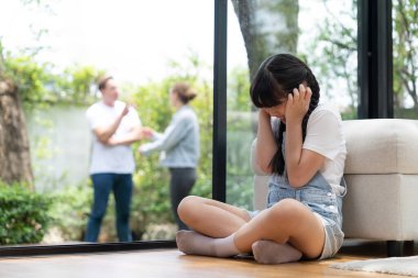 Stressed and unhappy young girl huddle in corner, cover her ears blocking sound of her parent arguing in background. Domestic violence at home and traumatic childhood develop to depression. Synchronos clipart