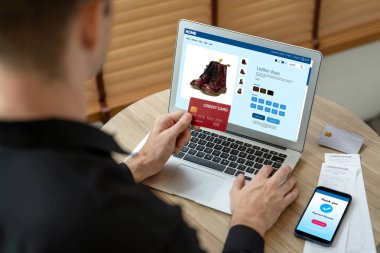 Genç adam internet bankacılığı için kredi kartlı dizüstü bilgisayar kullanıyor. İnternet üzerinden alışveriş yapıyor. Banka kartıyla modern ve kullanışlı online satın alma. Açılıyor