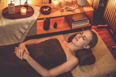 Beyaz kadın müşteri stres önleyici spa masajının keyfini çıkarıyor ve lüks otel ya da otelde sıcak mum ışığında güzellik teniyle eğleniyor. Sessiz.