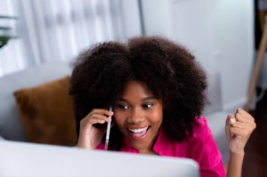 Afrikalı bir kadın telefonda iş arkadaşı ya da arkadaşıyla konuşuyor ve mutlu bir yüzle ekrana bakıyor. Şirketteki iyi haber hayatına sahip bir iş bulma konusunda başarı. Tatlandırıcı.