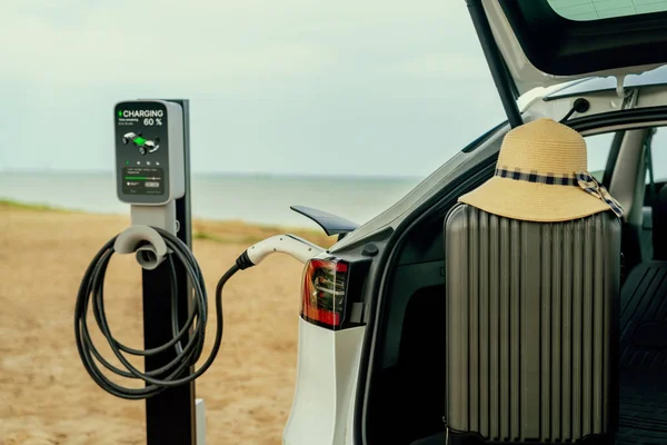 Road trip vacation traveling to the beach with electric car recharging battery with alternative eco-friendly and clean energy. Natural travel with EV car for sustainable environment. Perpetual