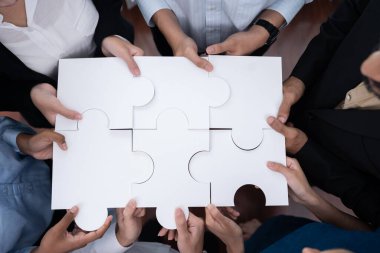 Çeşitli şirket çalışanları, ortaklık ve takım çalışmasını temsil etmek için bulmaca parçalarını birleştirerek ofiste işbirliği yapıyor. Yapboz 'u birleştirerek iş dünyasındaki birlik ve sinerji. Uyum