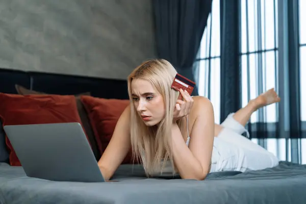 Stress worried young woman sit at table, as she pay bills online with credit card from financial debt problem, monthly expense and credit card debt. Over spending money problem lifestyle . Blithe
