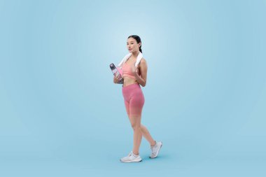 Atletik ve sportif Asyalı kadın yoğun kardiyo antrenmanından sonra dinleniyor ve su içiyor. Stüdyoda sağlıklı egzersiz ve vücut bakımına uygun yaşam tarzı takibi izole edilmiş bir arka plan. Kuvvetli