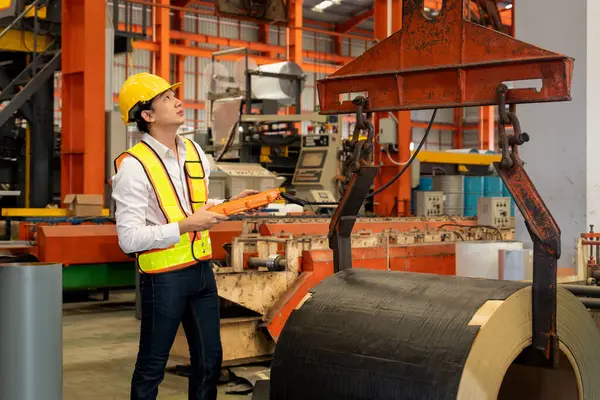 Makine operatörü çelik üretim makinelerini ustalıkla çalıştırıyor, metal fabrikasındaki ağır inşaat mühendisliği malzemeleri için silindir rulo çelik üretiyor. Örnek gösteriliyor