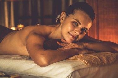Beyaz kadın müşteri stres önleyici spa masajının keyfini çıkarıyor ve lüks otel ya da otelde sıcak mum ışığında güzellik teniyle eğleniyor. Sessiz.