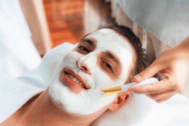 Kaplıca salonunun sakin atmosferi, insan müşterisi modern gün ışığında lüks yüz kremi masajıyla kendini yenileme zevkine kapılıyor. Yüz bakımı ve güzellik konsepti. Sessiz.