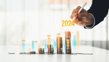 Büyüyen madeni para yığını iş yatırımını ve ekonomik büyümeyi simgeliyor. Finansal hedefe ulaşmak ve 2024 yılına maksimum kar sağlamak için finansal planlama yapan iş adamları. Kurnaz.
